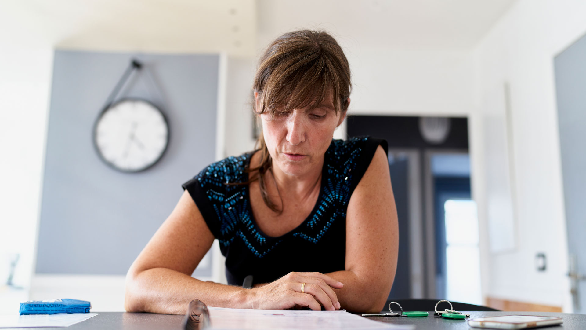 A woman at home reading the agency agreement with her real estate agent.