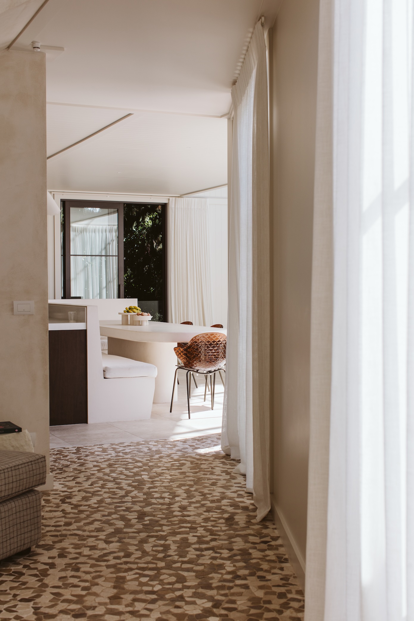 Pavers flow across the threshold and into the hallway. Bench seating in the booth is augmented by Calligaris Saint Tropez dining chairs in transparent chocolate.