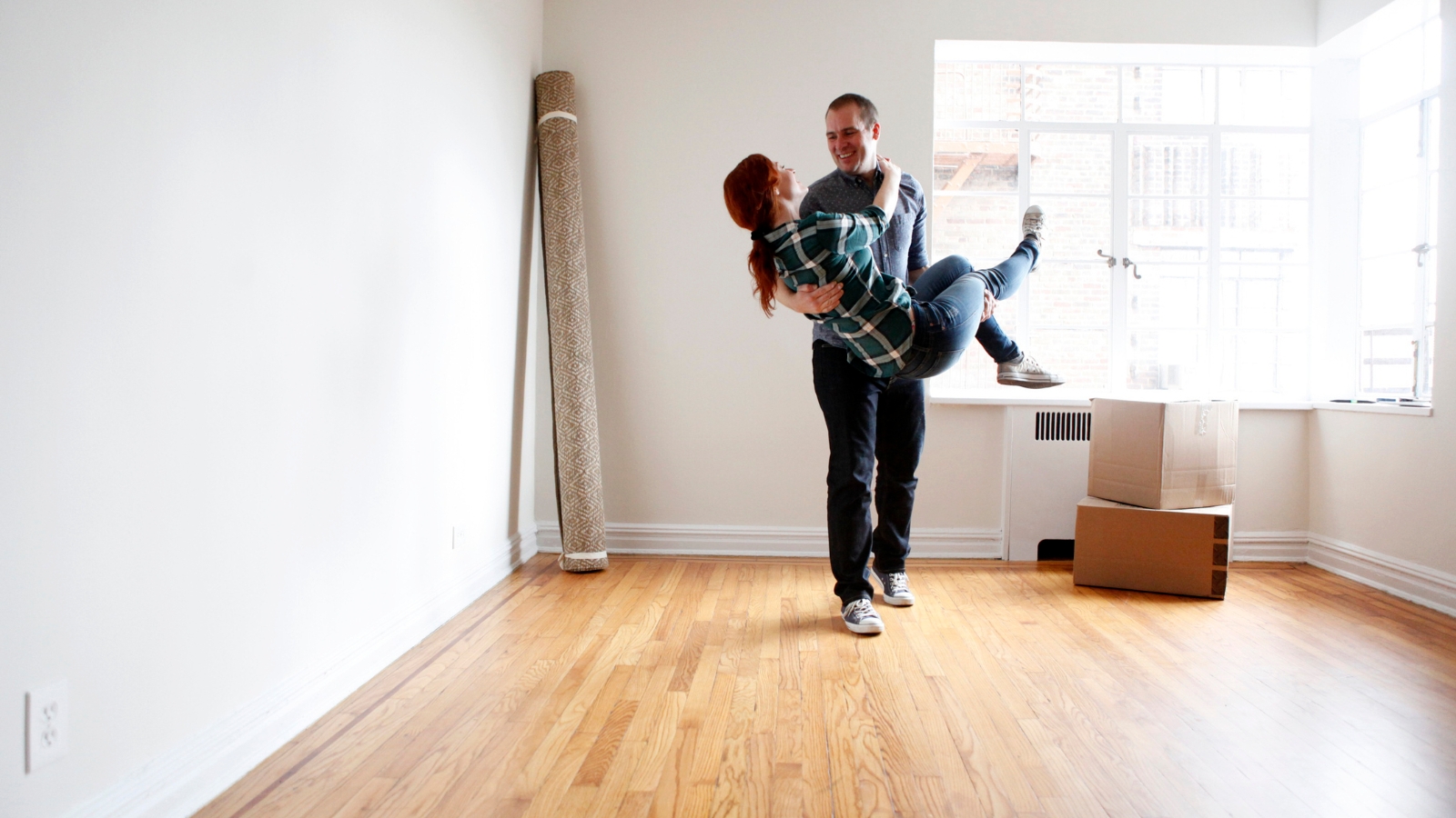 Man holding women in arms in new house. 