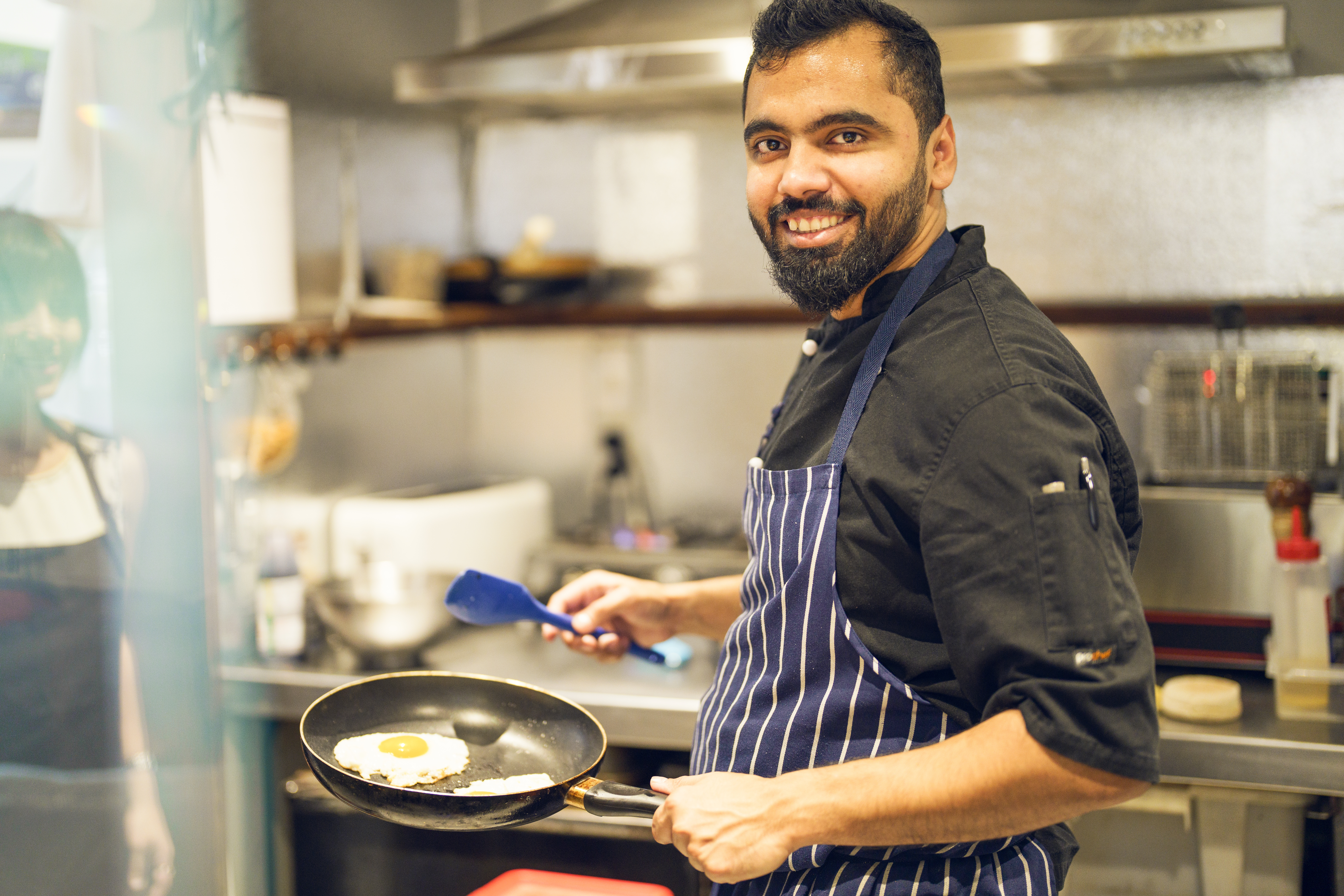 Man cooking eggs in a commercial kitchen. Chef.