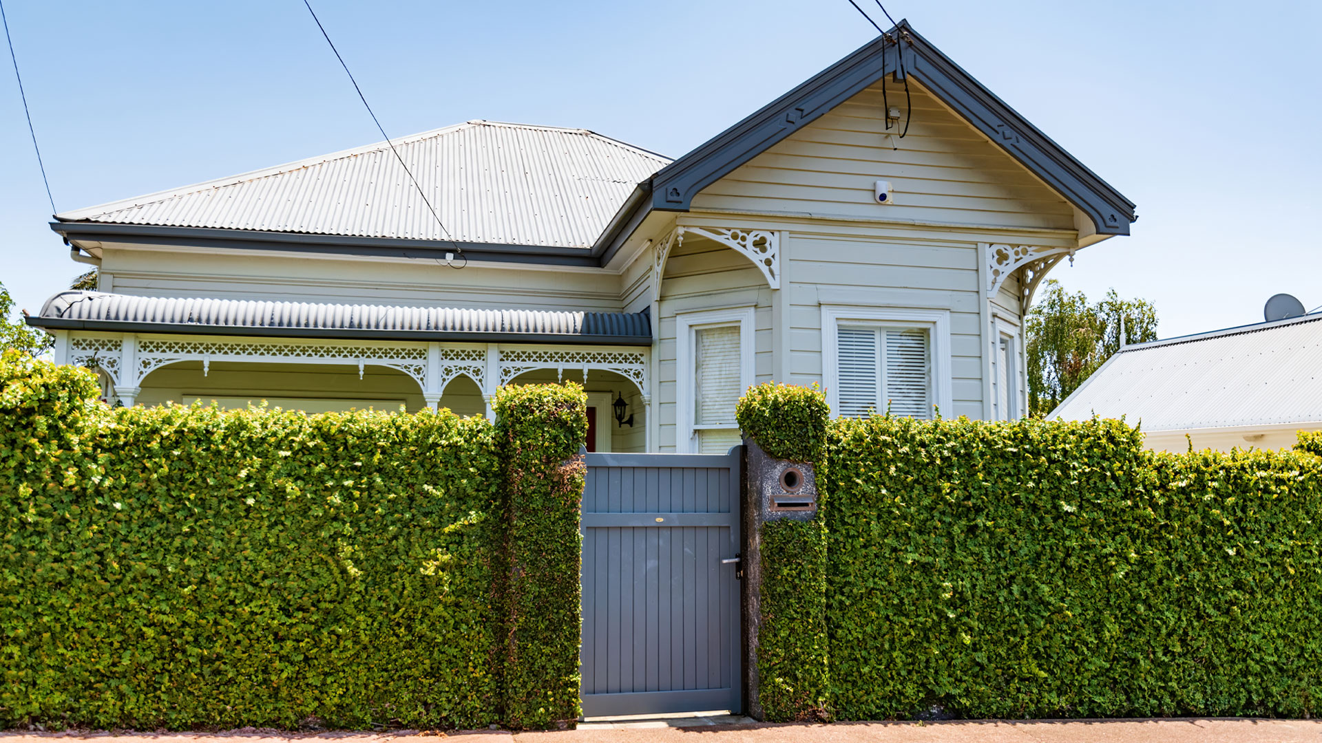 The exterior of a property behind a green hedge viewed from the street.
