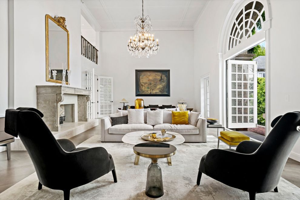 Luxury interior with high ceilings, fireplace, crystal chandelier, and contemporary furnishings.