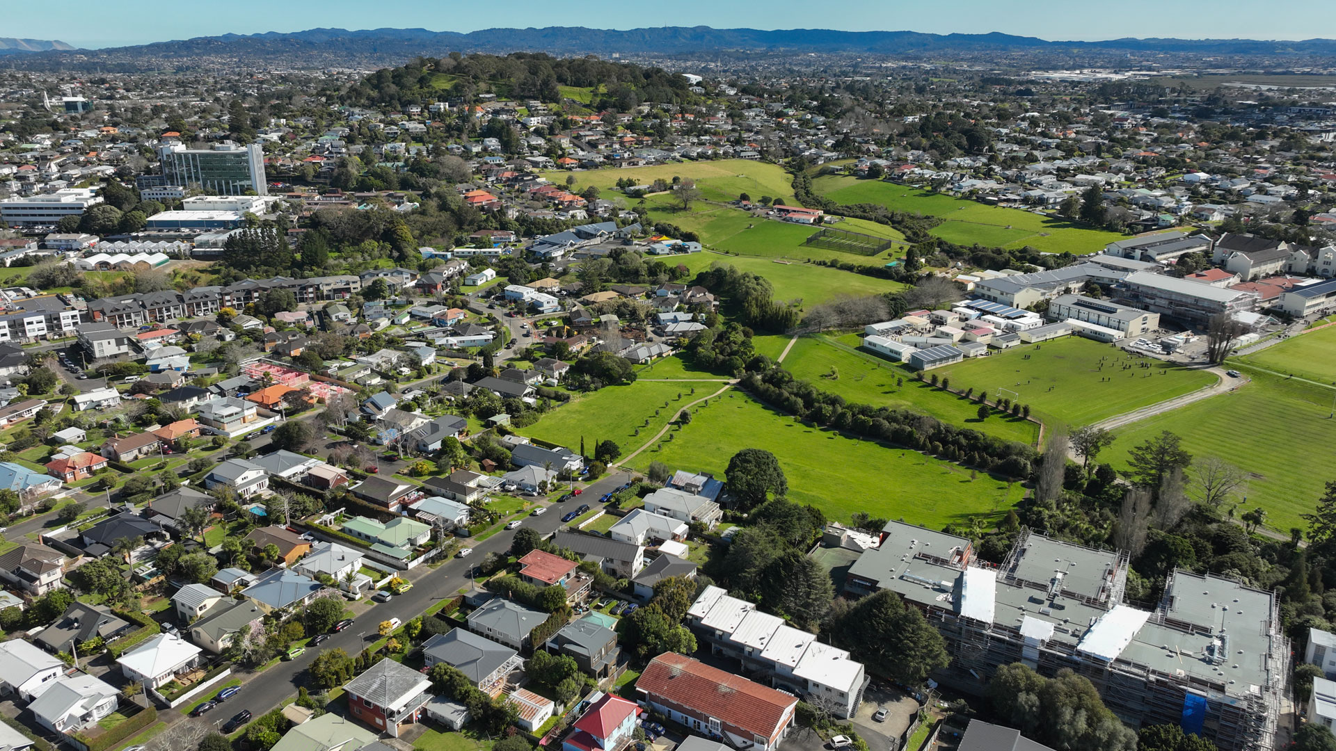 An aerial view of a suburb in Auckland showing the properties around areas of green.