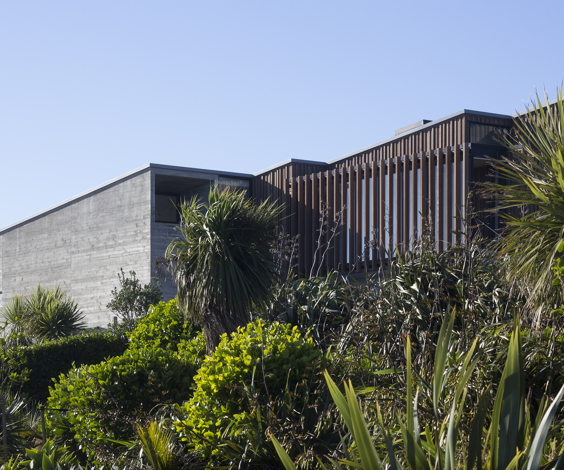 A concrete and wood home surrounding by folliage.