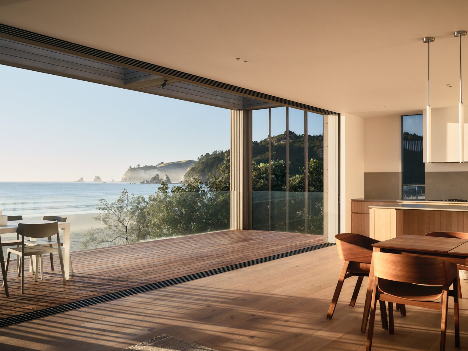 Timber flooring in the open-plan kitchen dining area transitions seamlessly to the timber deck, creating a harmonious link between the two spaces. Image: Zico O’Neill