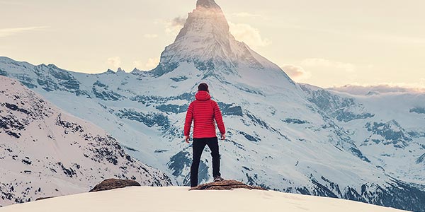 Climber looking at a mountain peak, symbolising an employee and the company’s goals.