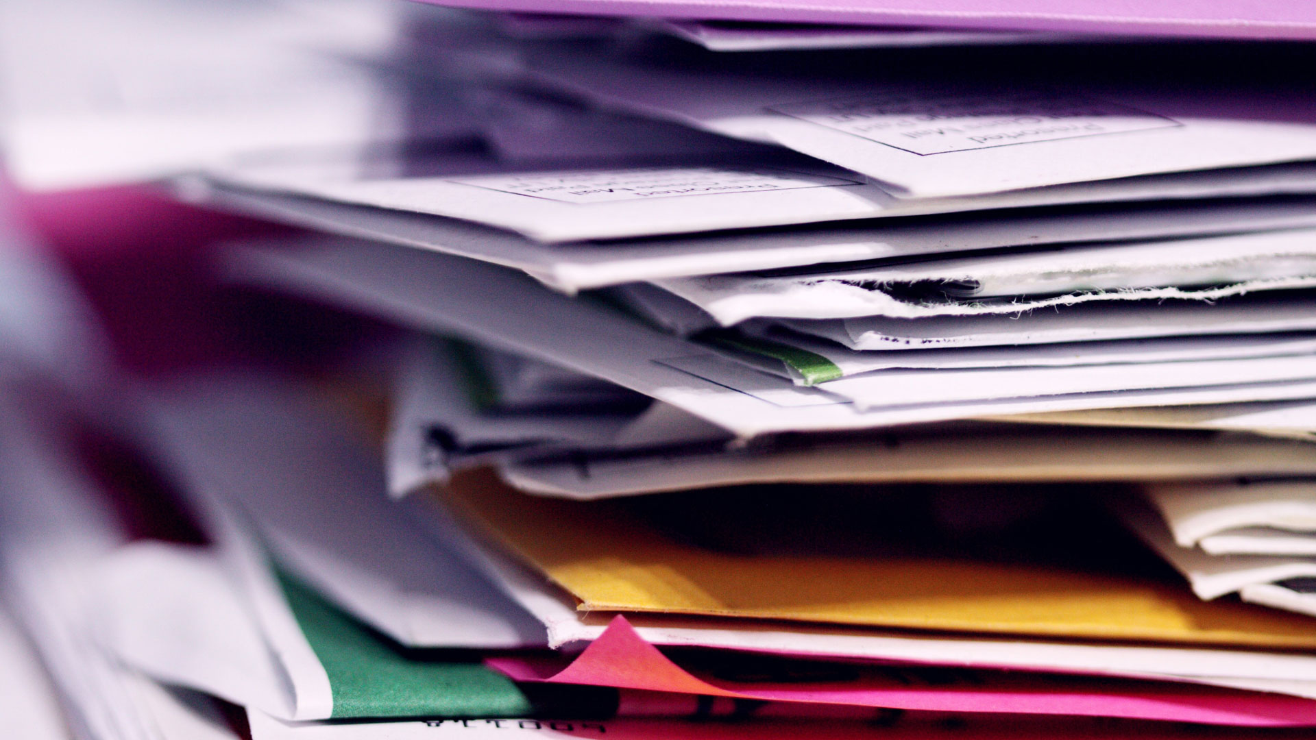 Stack of papers in folders on a desk.