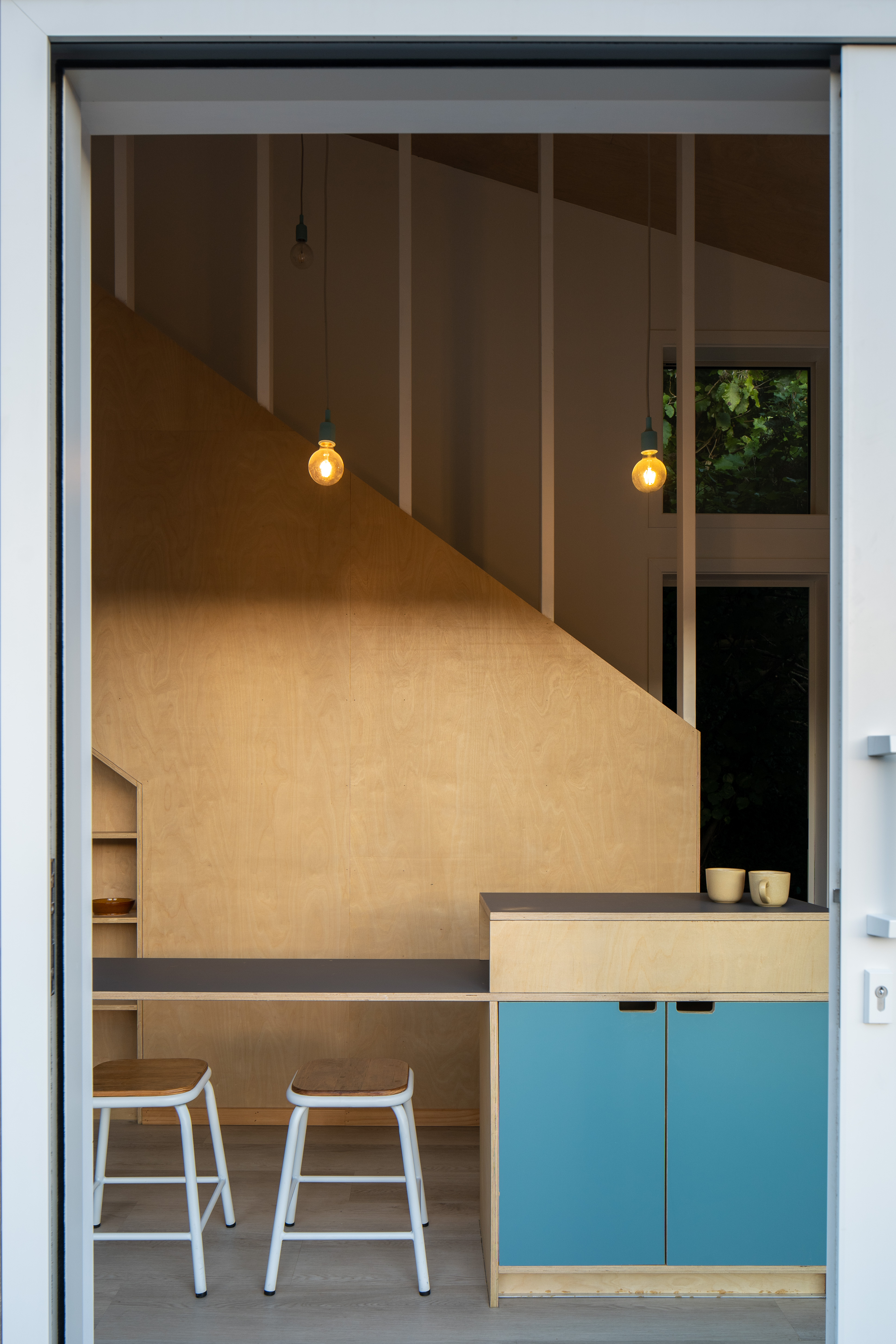 In the 2024 Small Home of the Year, the kitchen island doubles as a workspace; storage is incorporated under the stairs – each space versatile and multi-functional to make the most of the compact footprint. Image: Paul Brandon