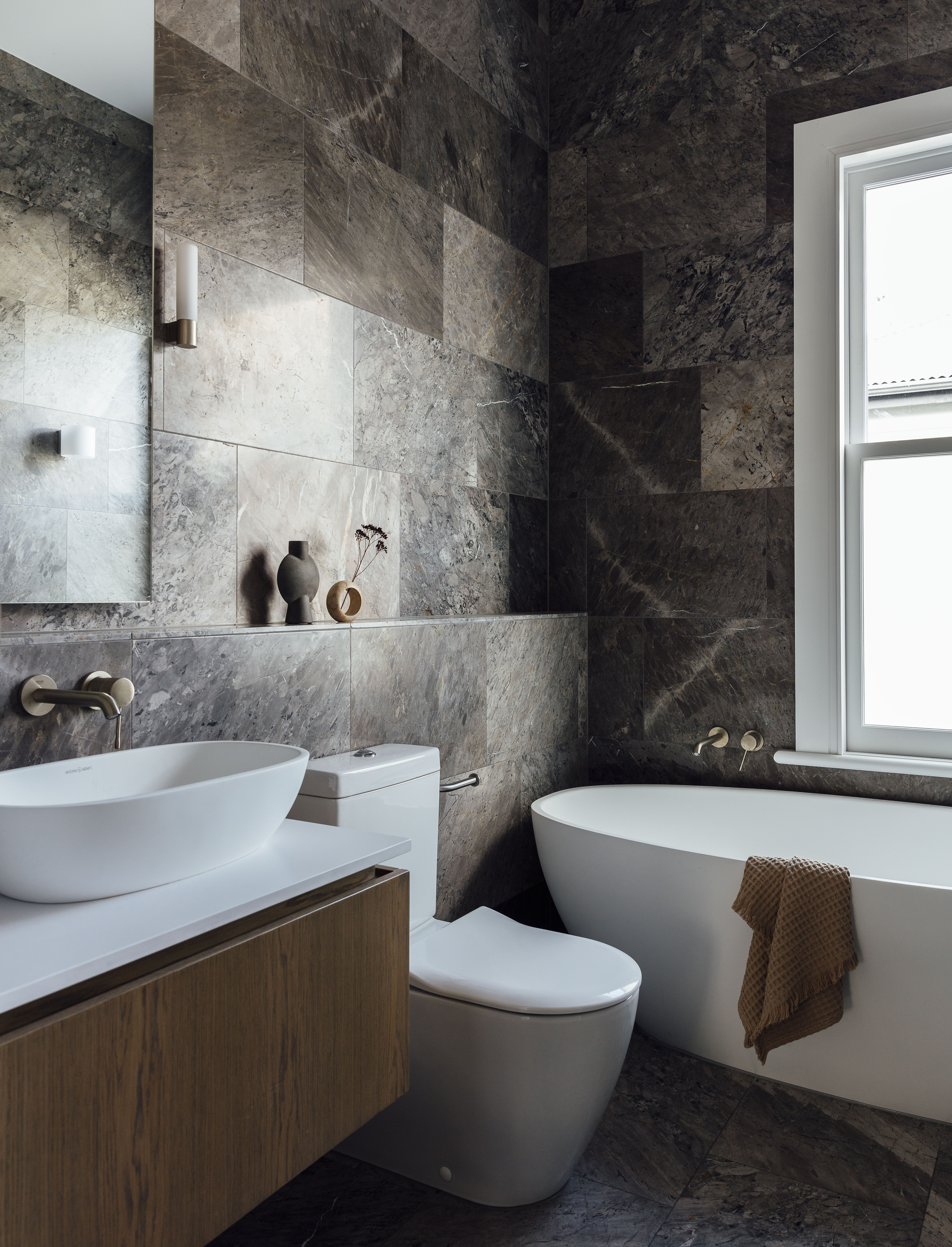 Both this bathroom and the ensuite are compact, so Karen knew she wanted to use a single stone for the walls and floors, something earthy and dramatic. ‘I chose azzurro marble from Artedomus, which like the kitchen stone has copper veining and an underlying warmth. ‘You can’t go wrong if you stick with nature’ was my motto.’ Enhancing its beauty is Essence tapware by Grohe from Robertson, a vanity by Cube Dentro, a Bari light by Astro Lighting from ECC and a vase by 101 Copenhagen from Frobisher Interiors. The Nought stem holder beside it and the towel on the Barcelona bath by Victoria & Albert from Robertson are from Città.”