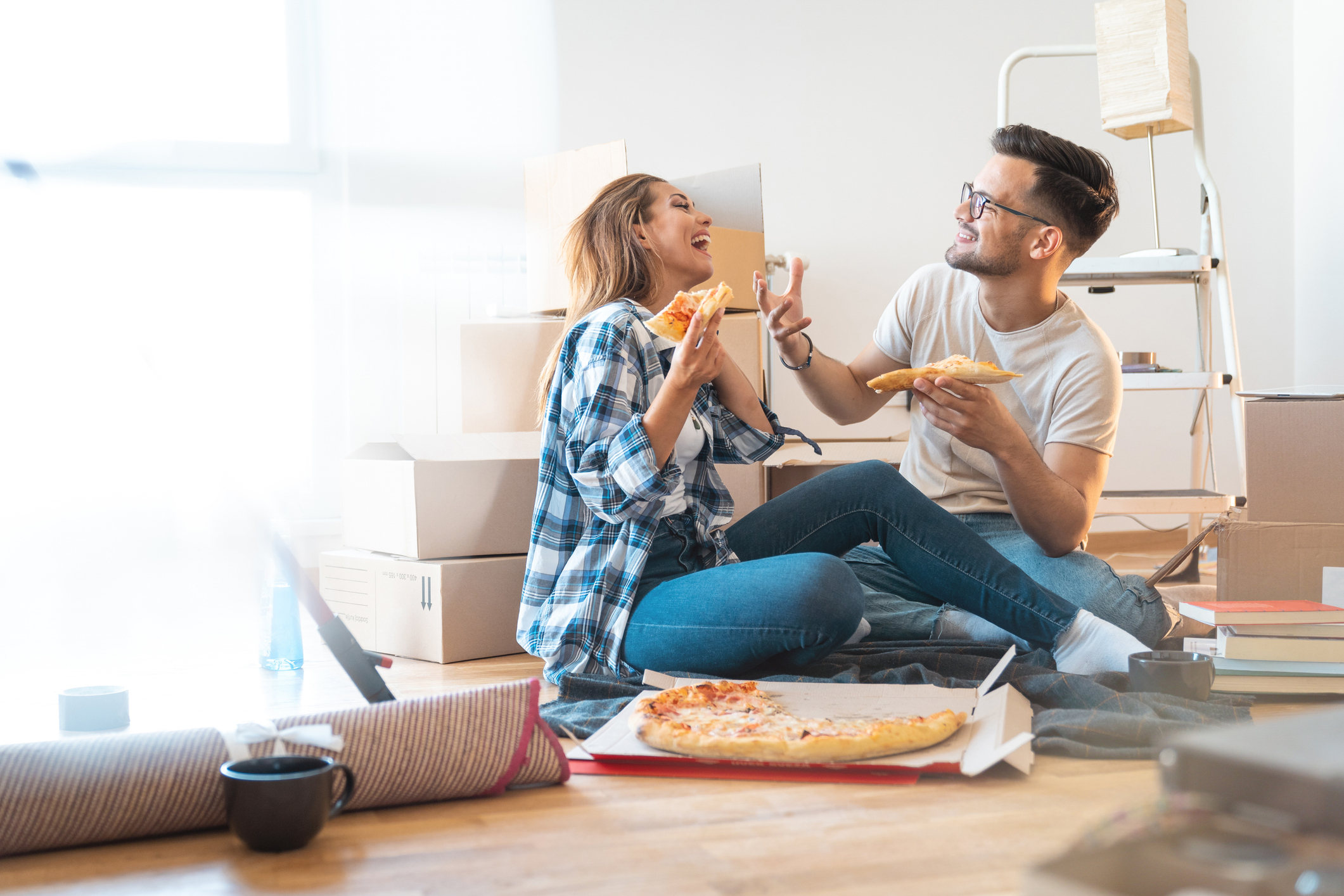 Couple eating pizza on the floor of their new home