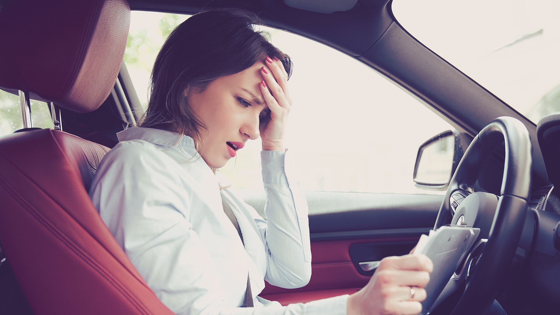 woman looking stressed behind wheel of car