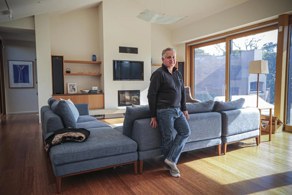 Owner of NZ passive house stands in living room