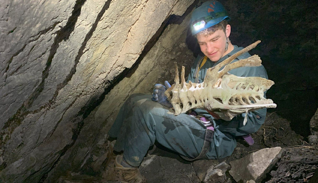 A boy holding the skeleton of a moa, found in a cave in an offgrid property in Tākaka.