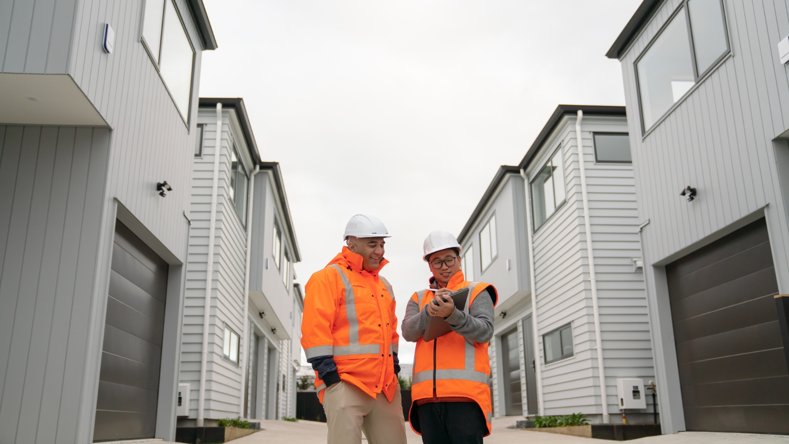 Two developers looking at clipbaord in front of houses.