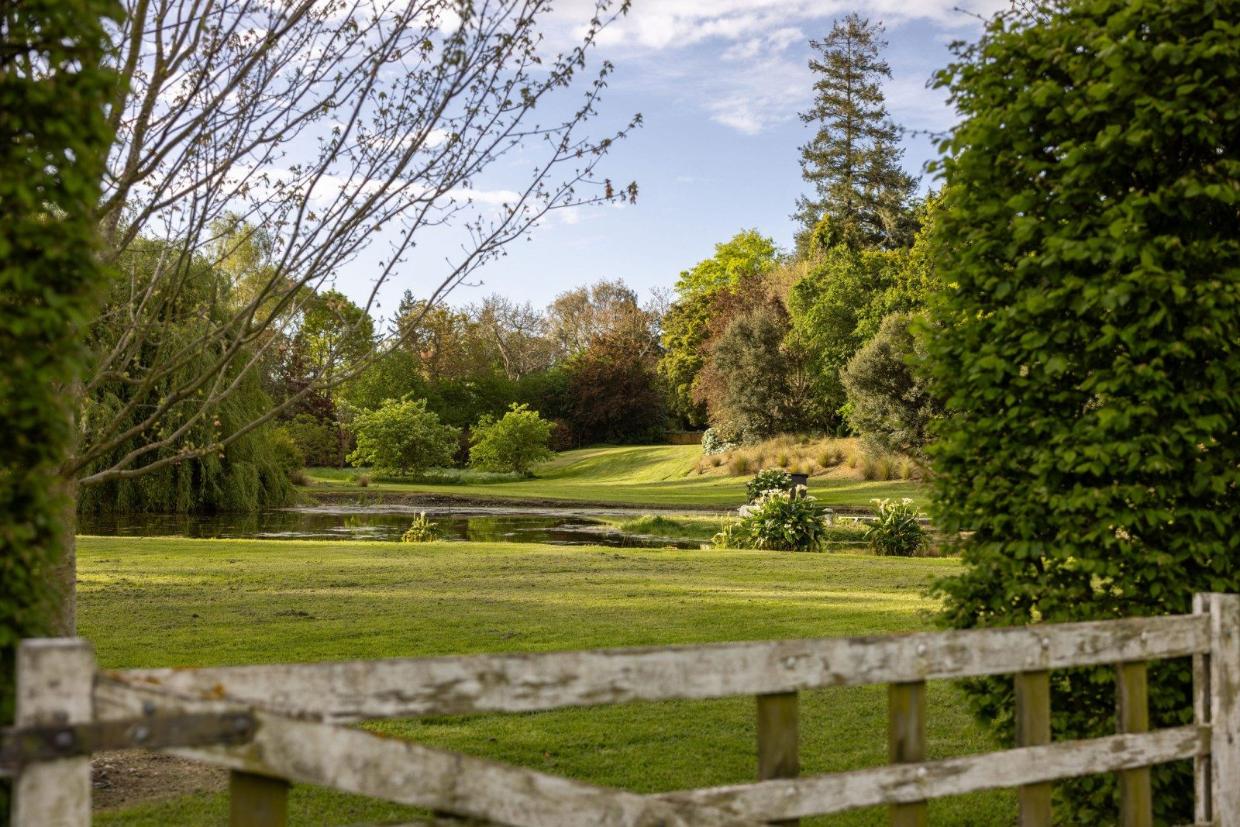 The property covers five hectares, with gardens, paddocks, a pond, and a variety of stunning trees.