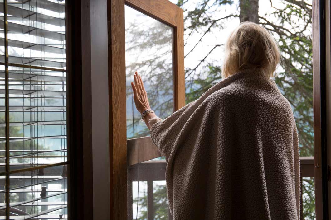 Woman standing in the open door of her house looking out at the New Zealand countryside.