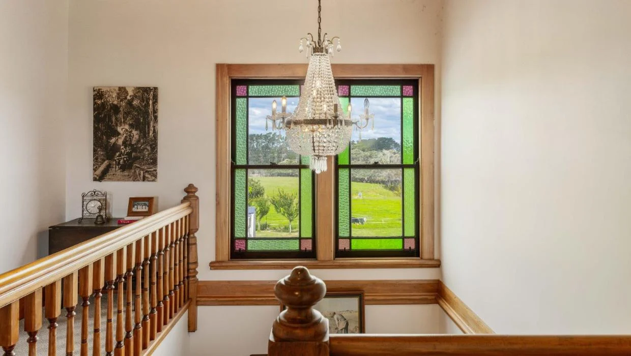 Original stained glass windows remain a key feature - this one framing a beautiful view at the top of the stairs.