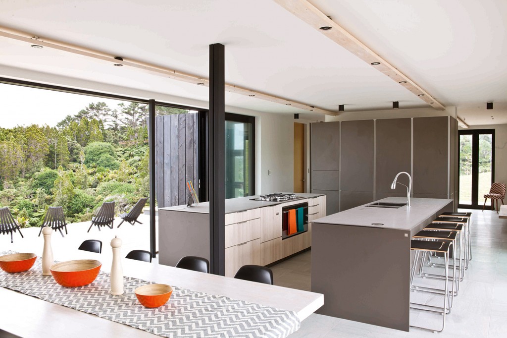 The geometry and palette of the kitchen complements the home. Two parallel island benches occupy the space, with a wall of cabinetry for more storage at one end. Photograph by Simon Wilson.