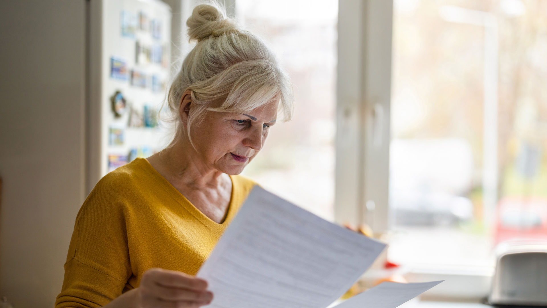 Woman reading her contract with a real estate agency at the home she is trying to sell.