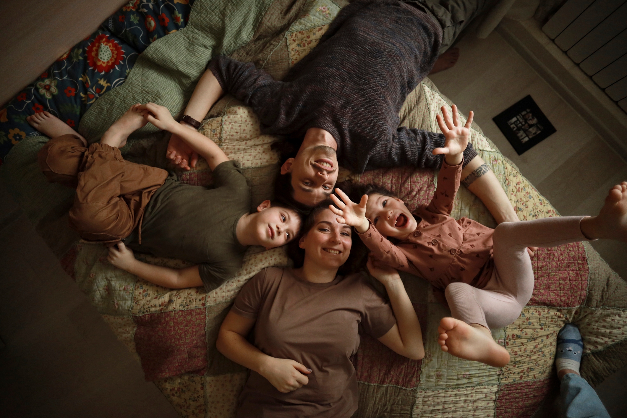 Family of four lie on the floor looking up at the ceiling smiling