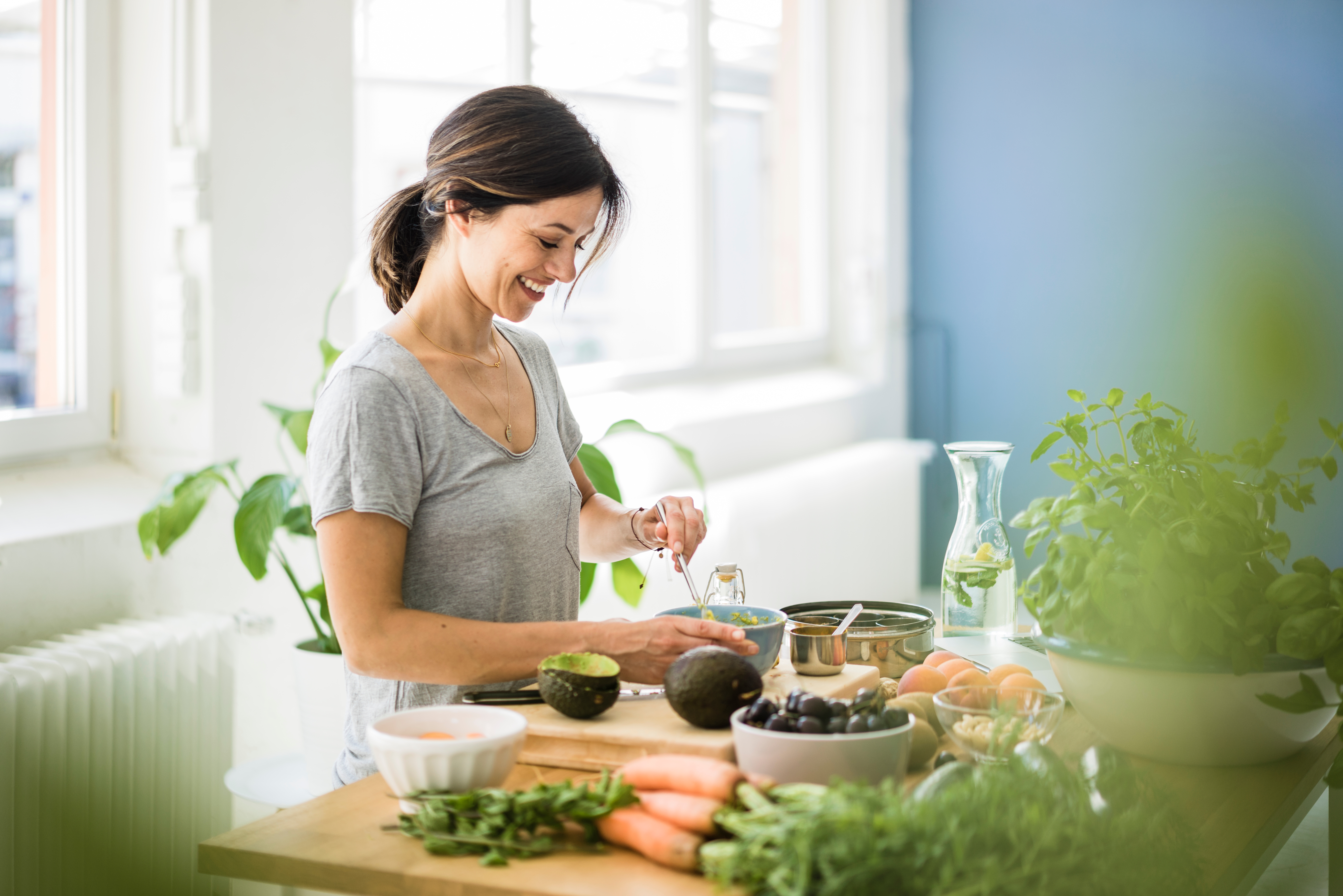 Woman preparing healthy salad in her kitchen.