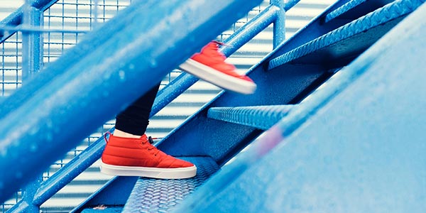 Red trainers climbing stairs, symbolising progress in the workplace.