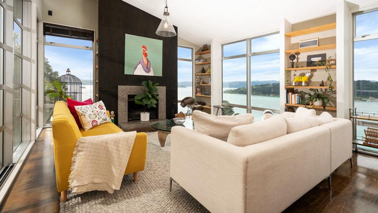 Wrap-around windows ensure the living area is filled with light. The woodburning fireplace was a drawcard for the owner. Photo: Lowe & Co