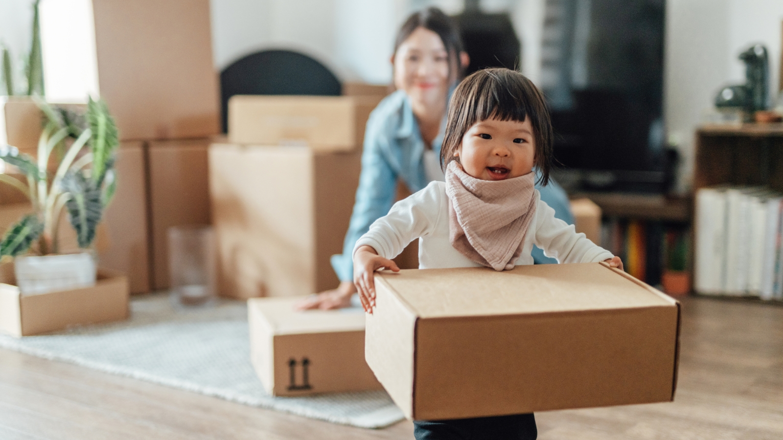 Girl running away from mum surrounded by moving boxes. 