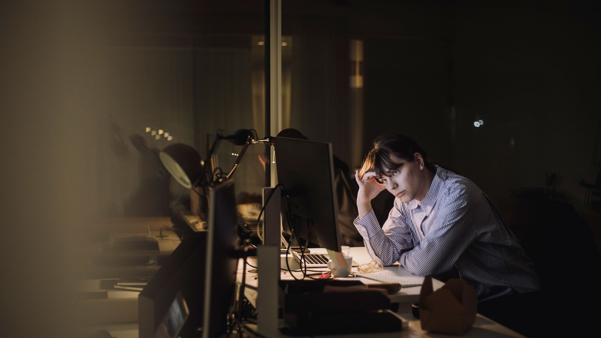 Woman working late in an office at night.