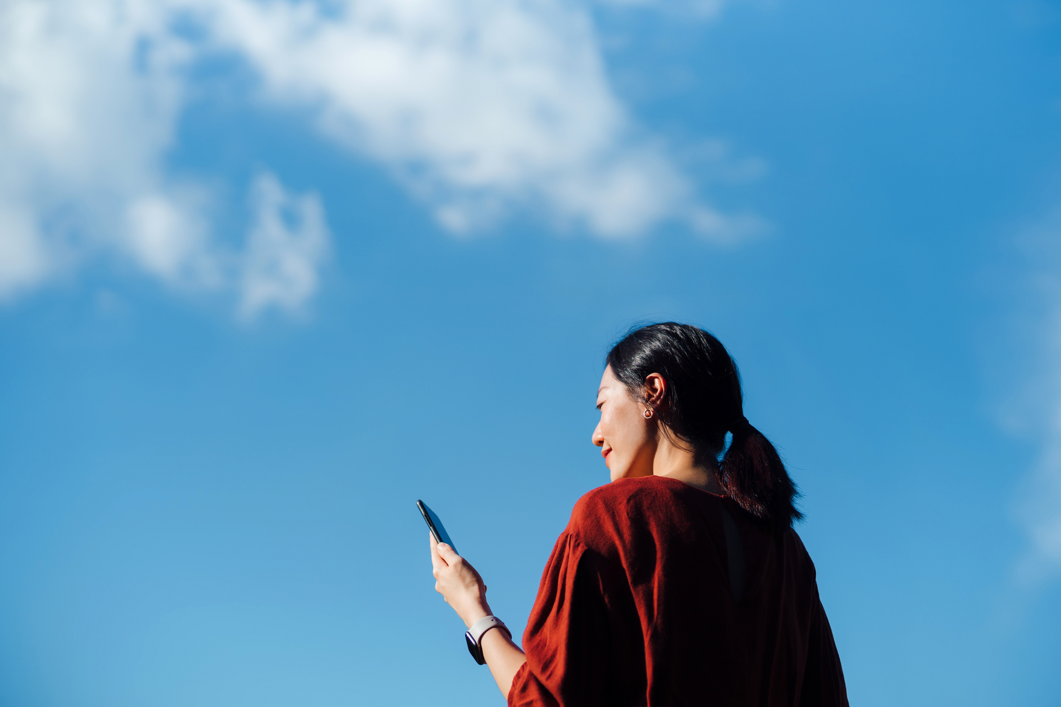 Woman looking at her phone with a blue sky behind