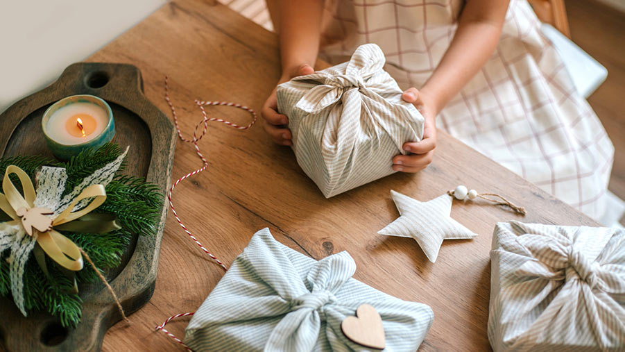 Girl wrapping presents in eco-friendly cloth in preparation for 