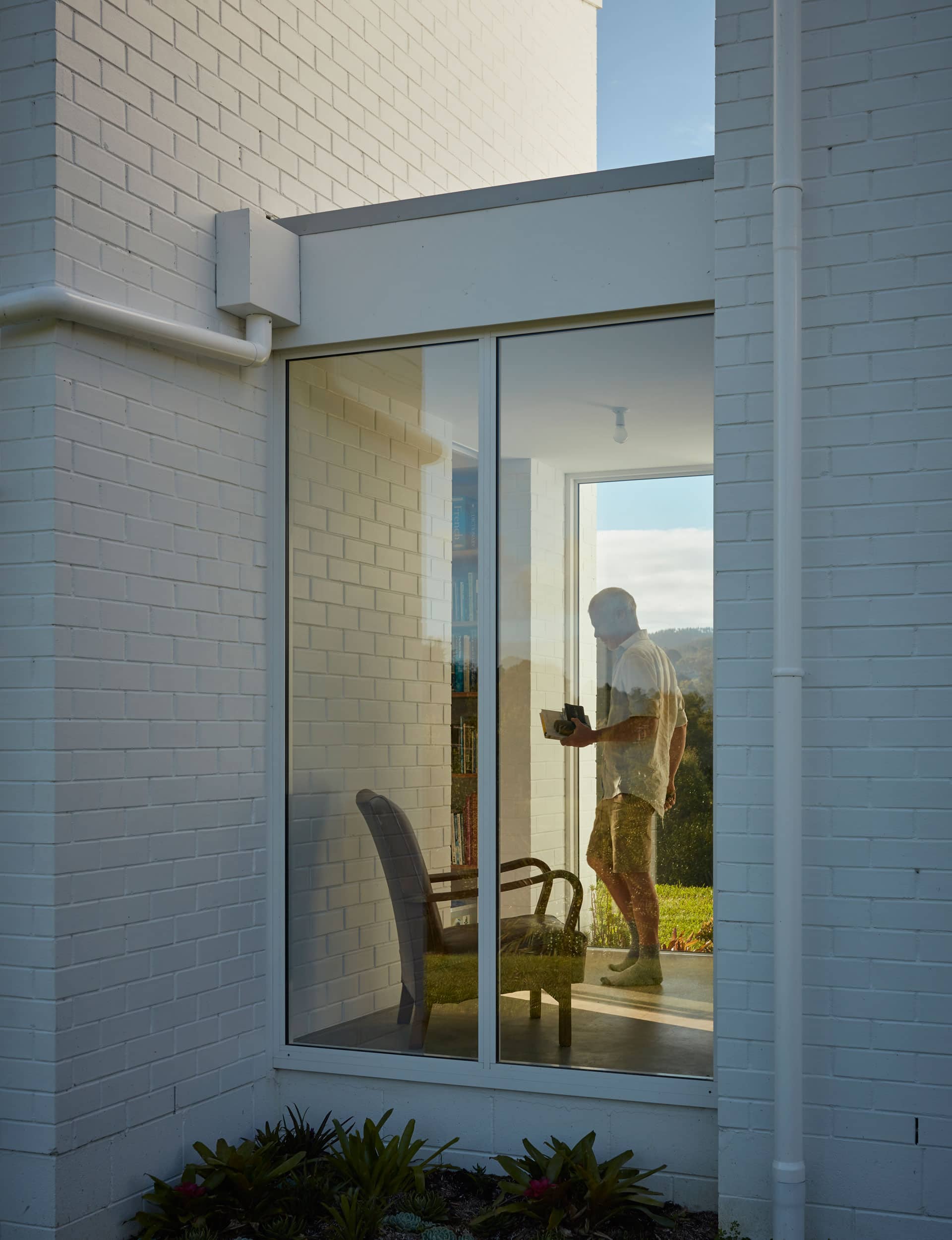 White brick home with neutral-coloured exterior, featuring clean lines and minimalistic white fittings, set against a clear sky.