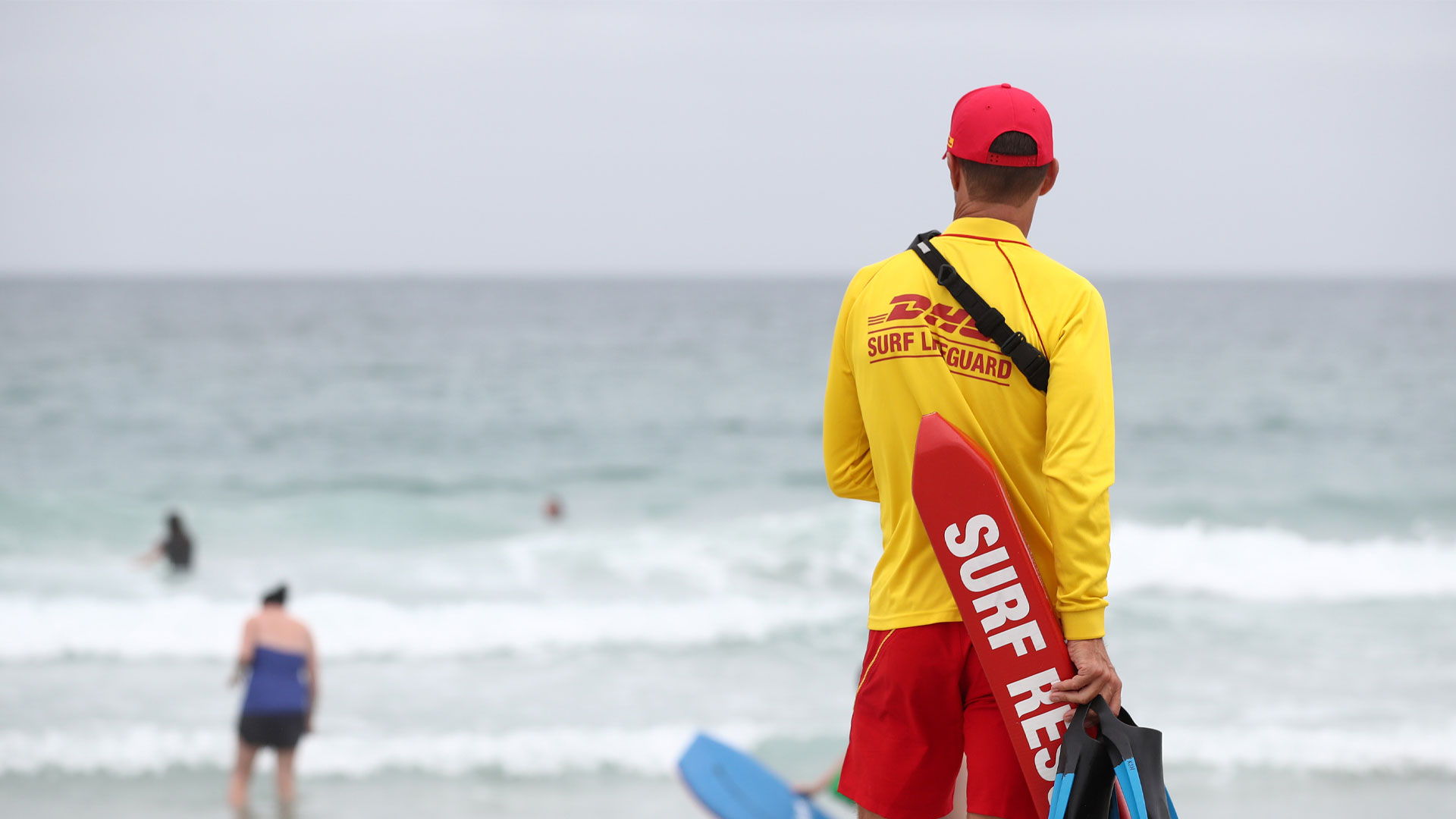 Surf lifeguard looking out over the ocean on a New Zealand beach.