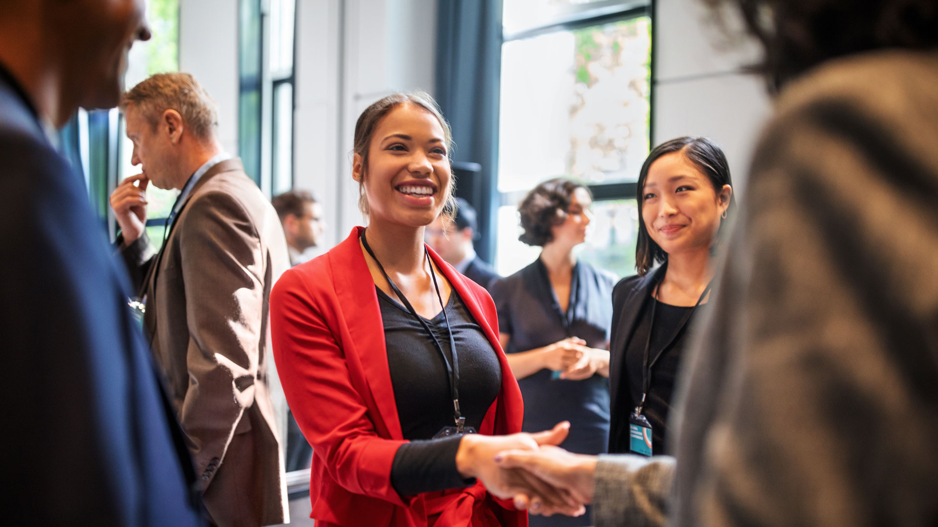 Two female professionals greeting each other at a networking event.