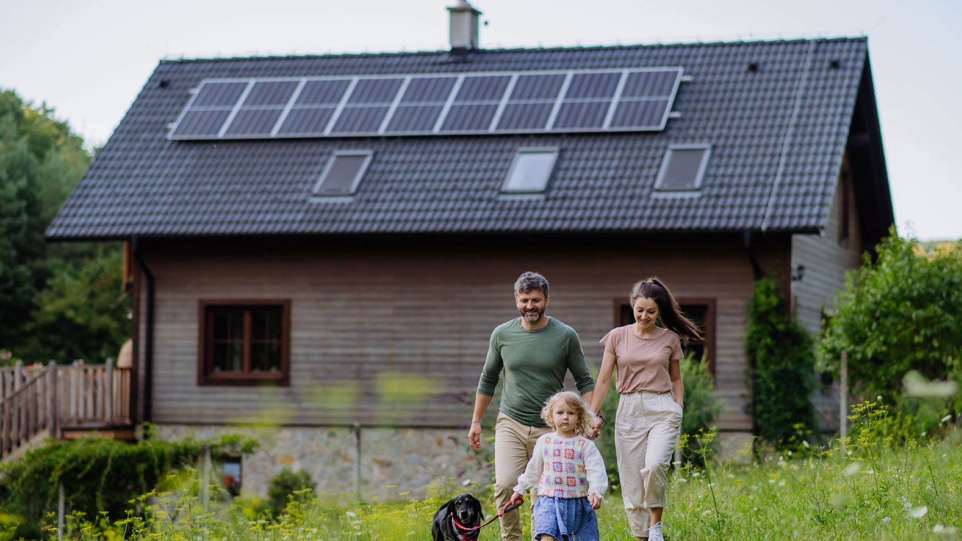 A family outside their home in rural New Zealand, with solar panels on the roof.