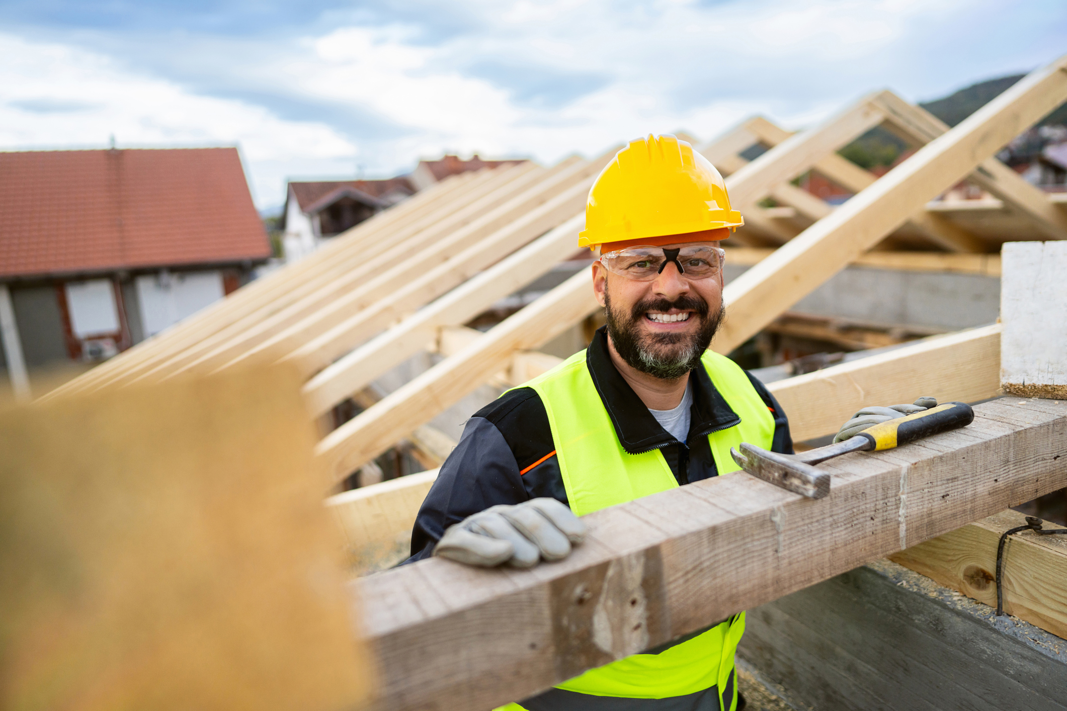 Male roofer smiling while standing in roof he is building
