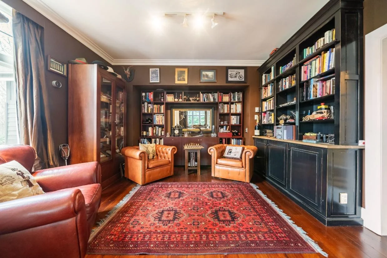 Photo of the study, lined with shelving. Dark-painted walls help to create a sense of intimacy.