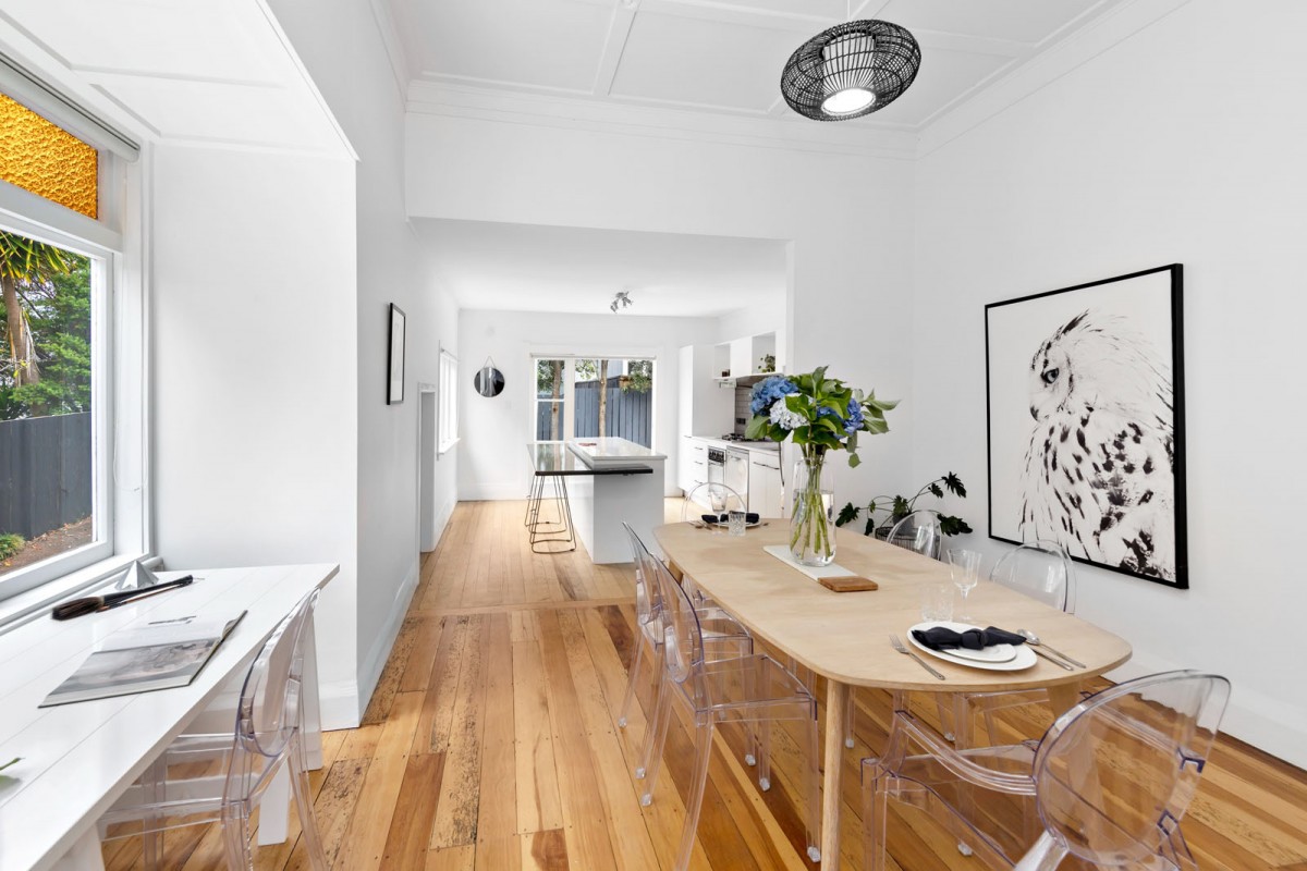 Dining room looking across to the kitchen. Large dining table with art on the wall.