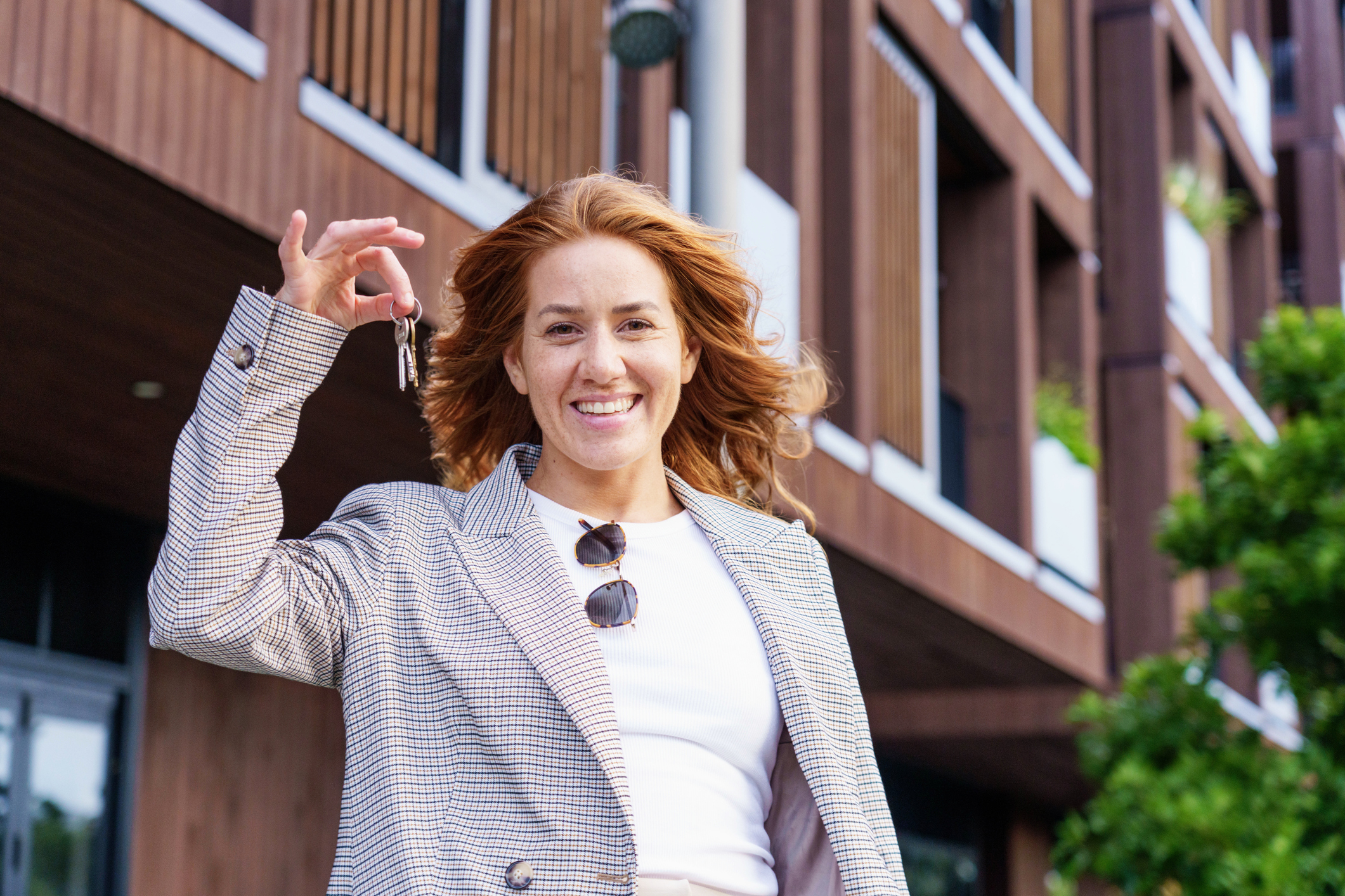 Young female real estate agent standing in front of property with keys in hand