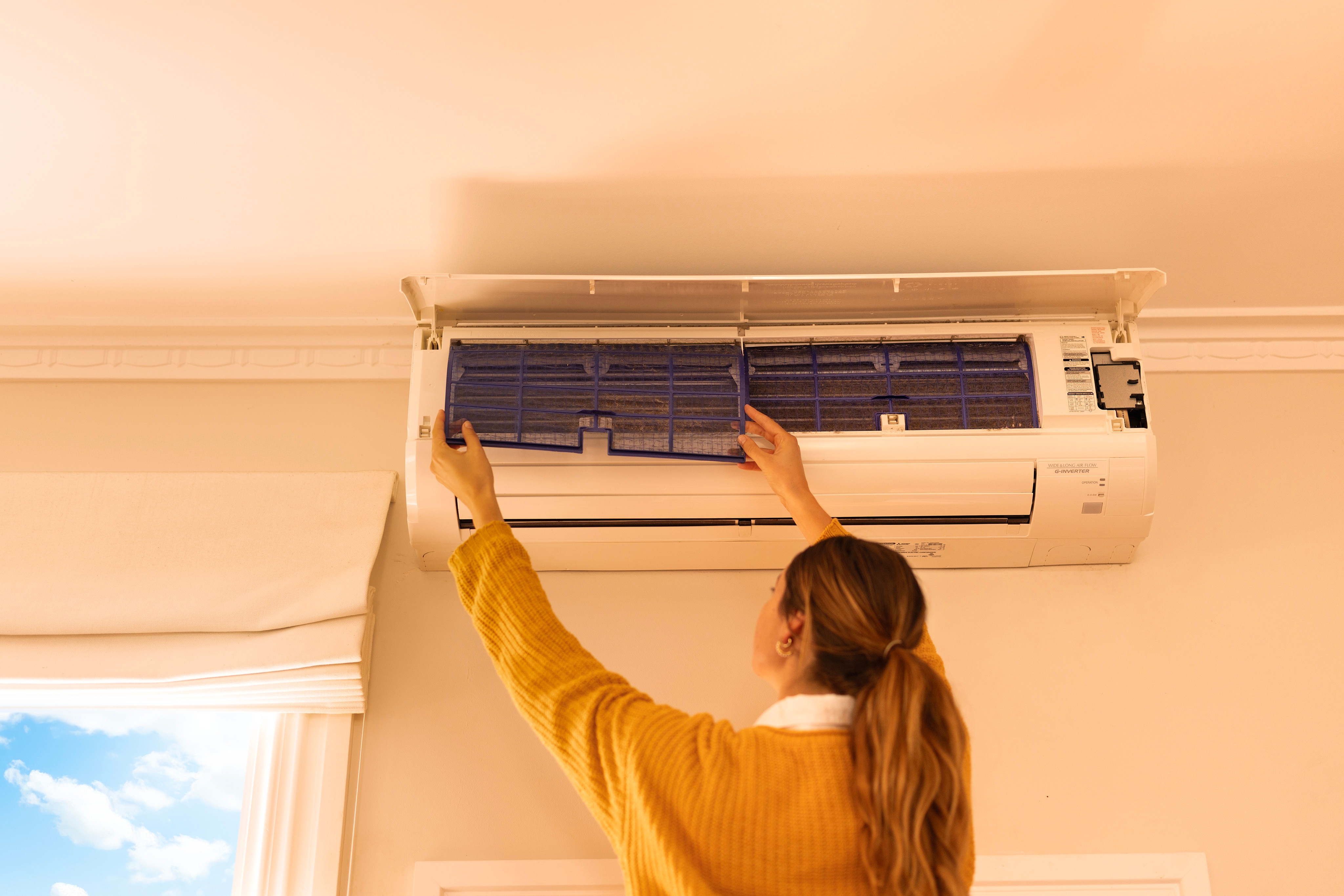 Woman takes out filters in her heat pump for cleaning