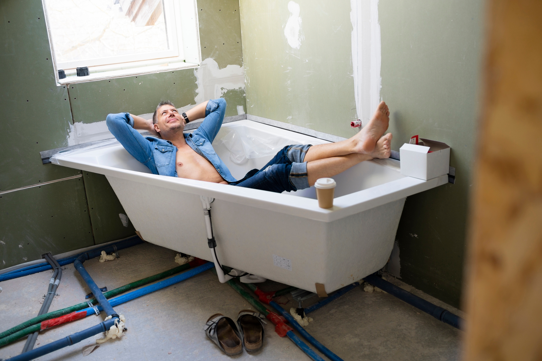 Man in bathtub with clothes on. 