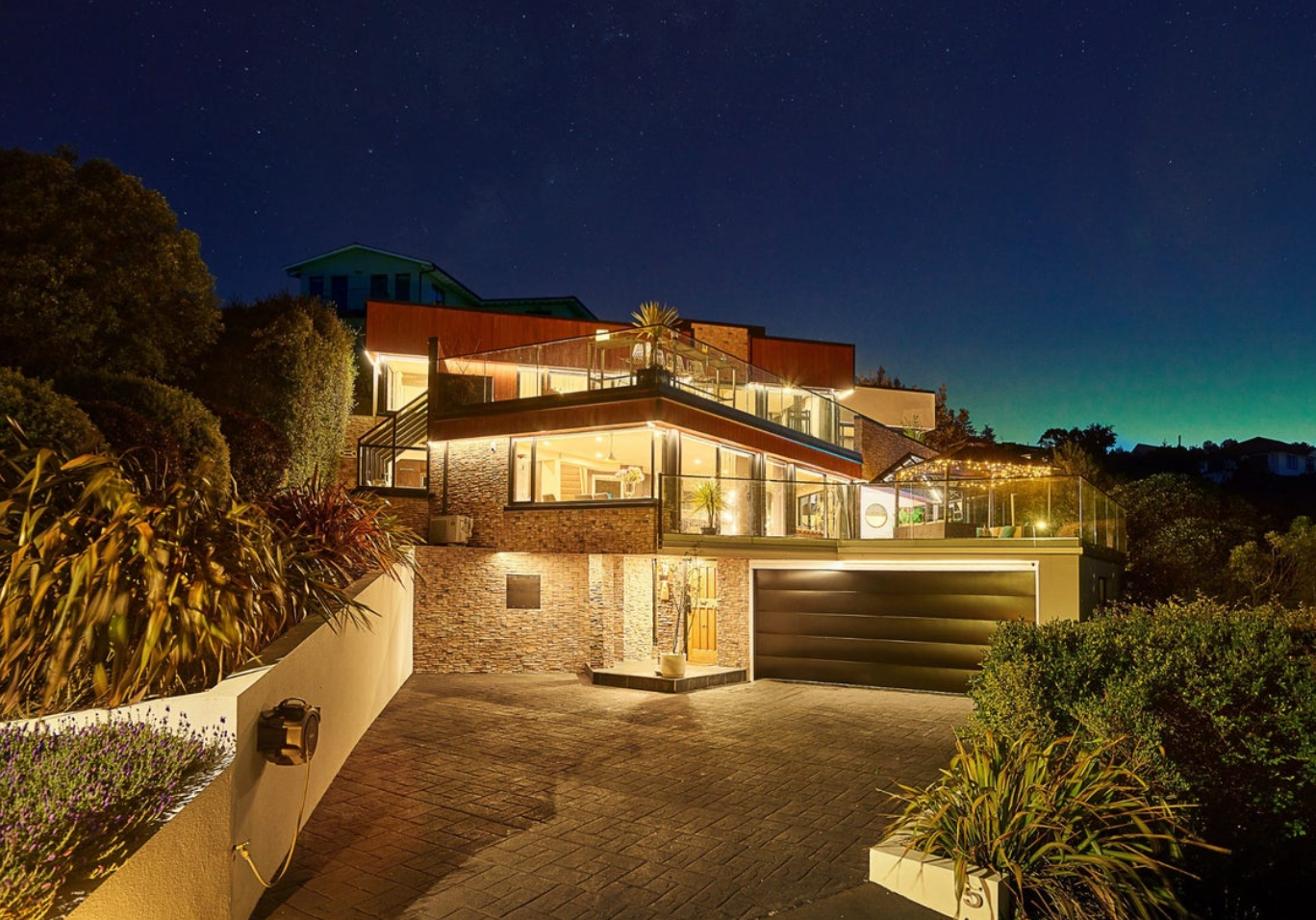 A photo of a house taking during the night with the house lit up with outdoor lights.