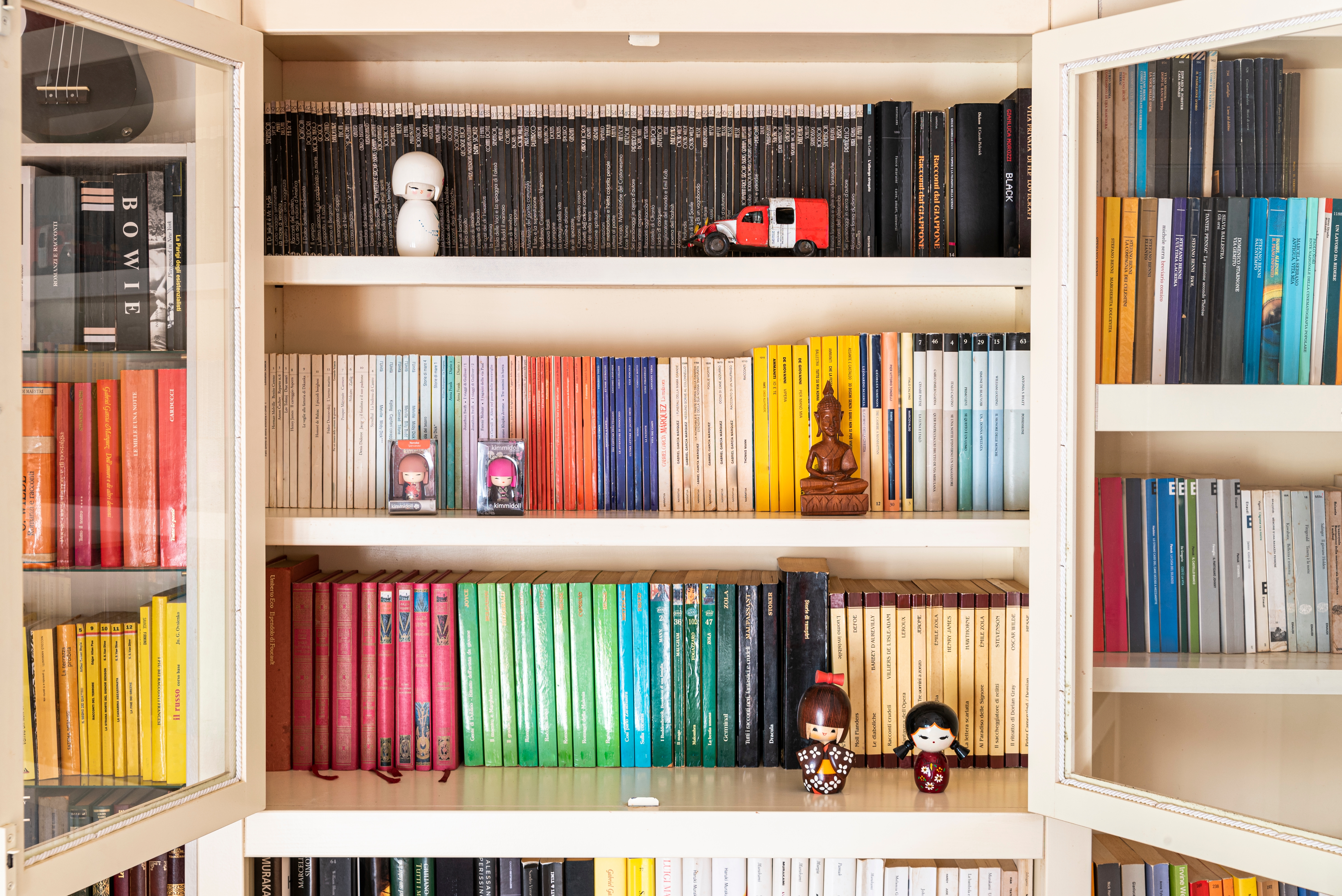 Colourful bookcase decorated with different small ornaments 