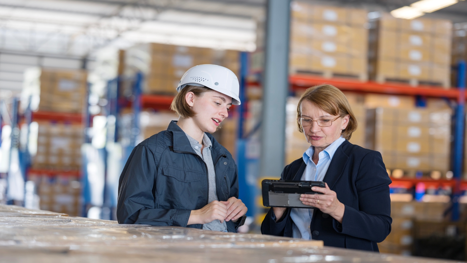 Two logistics professionals looking at a clipboard in a warehouse