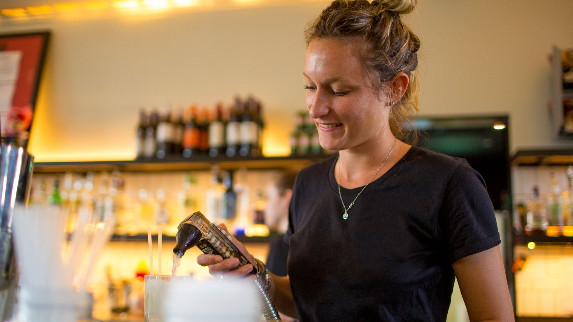 Female student bartender making drinks in a bar