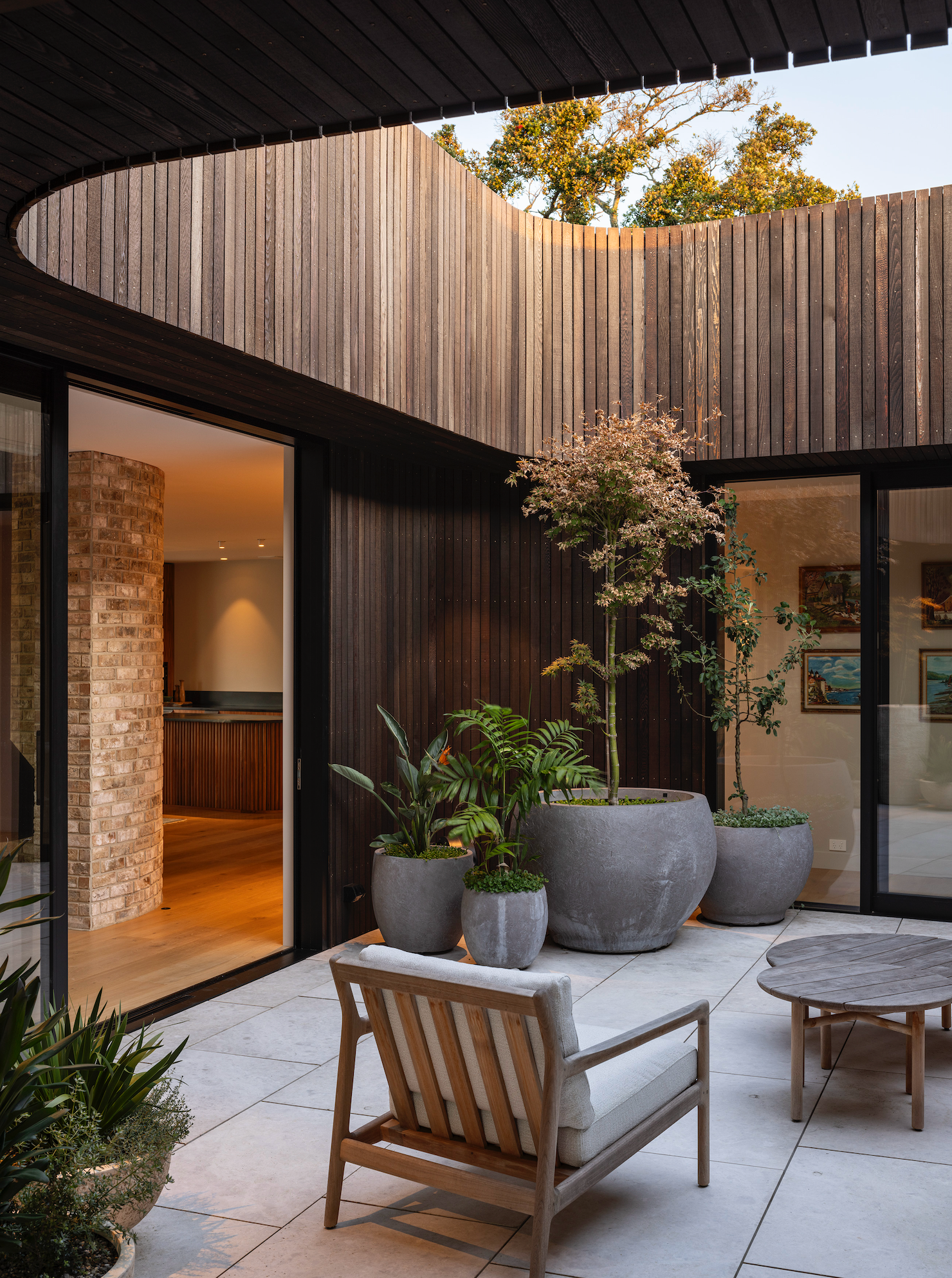 The 2024 Rural Home of the Year, Mangawhai Estuary House by Belinda George Architects, features an open air courtyard in which an array of luscious potted plants allow for connection to nature without having indoor plants. Image: Simon Devitt