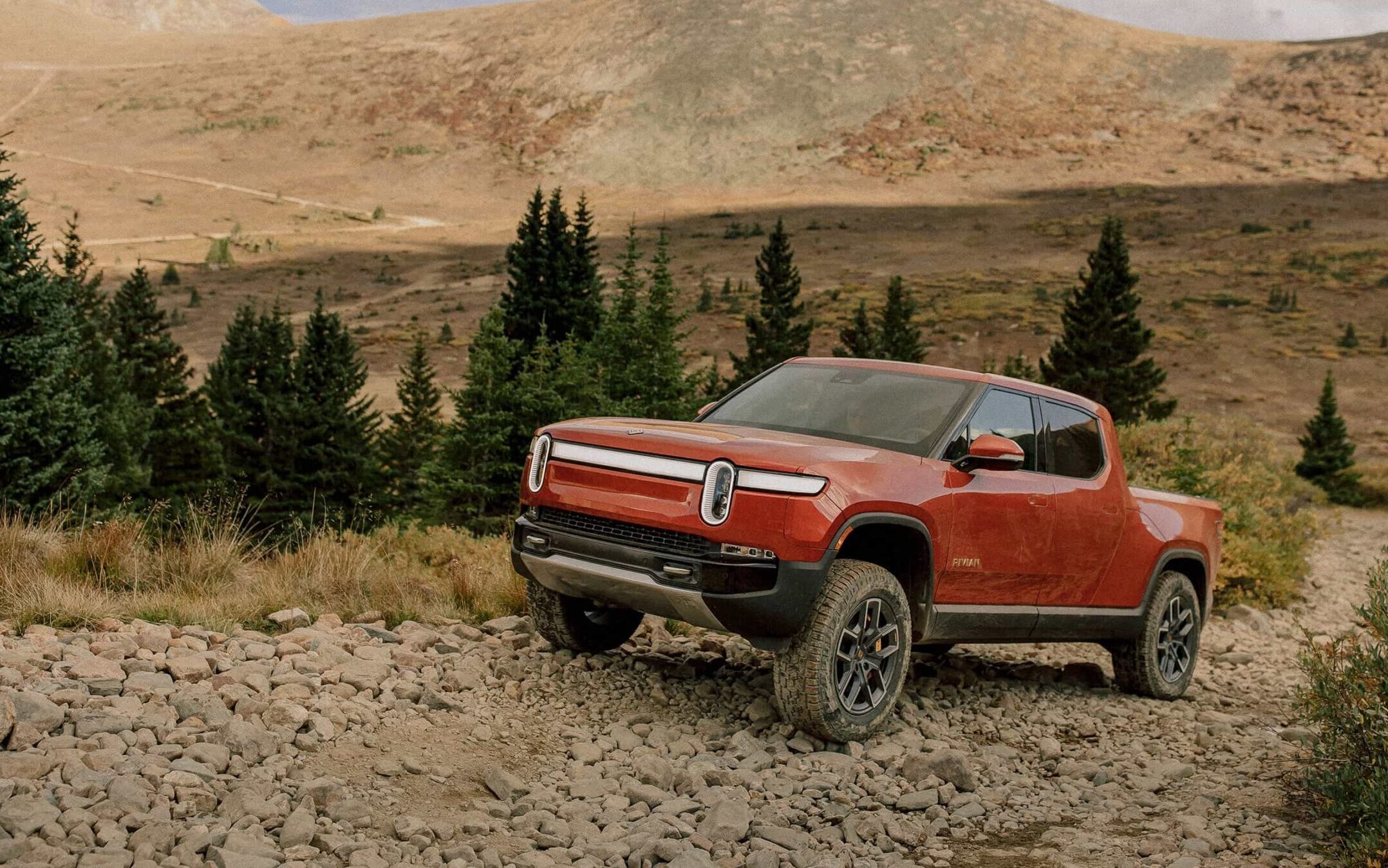 Red Rivian R1T on top of rock hill