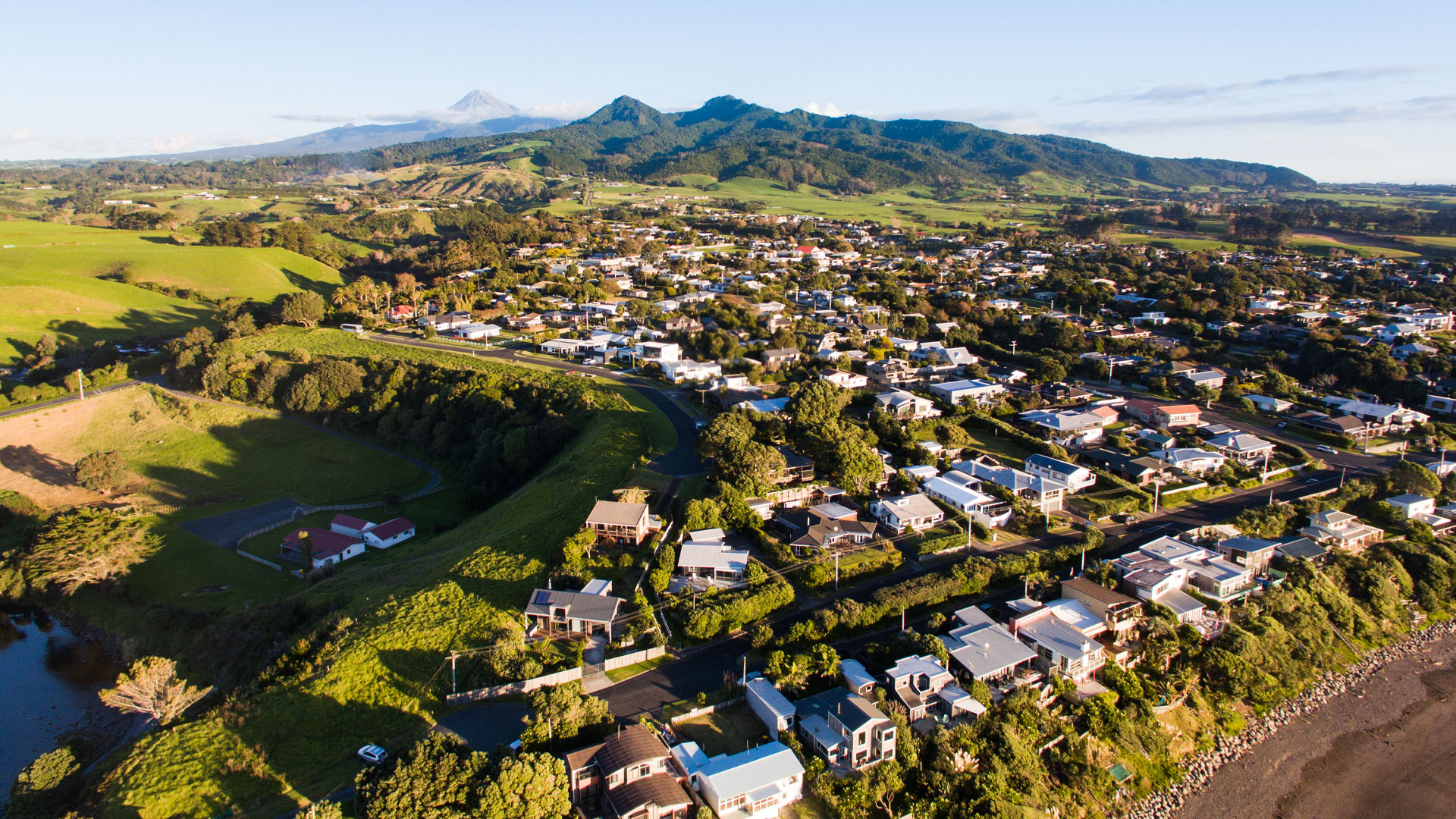 A photo of a town in Taranaki, with Mt. Taranaki in the background.