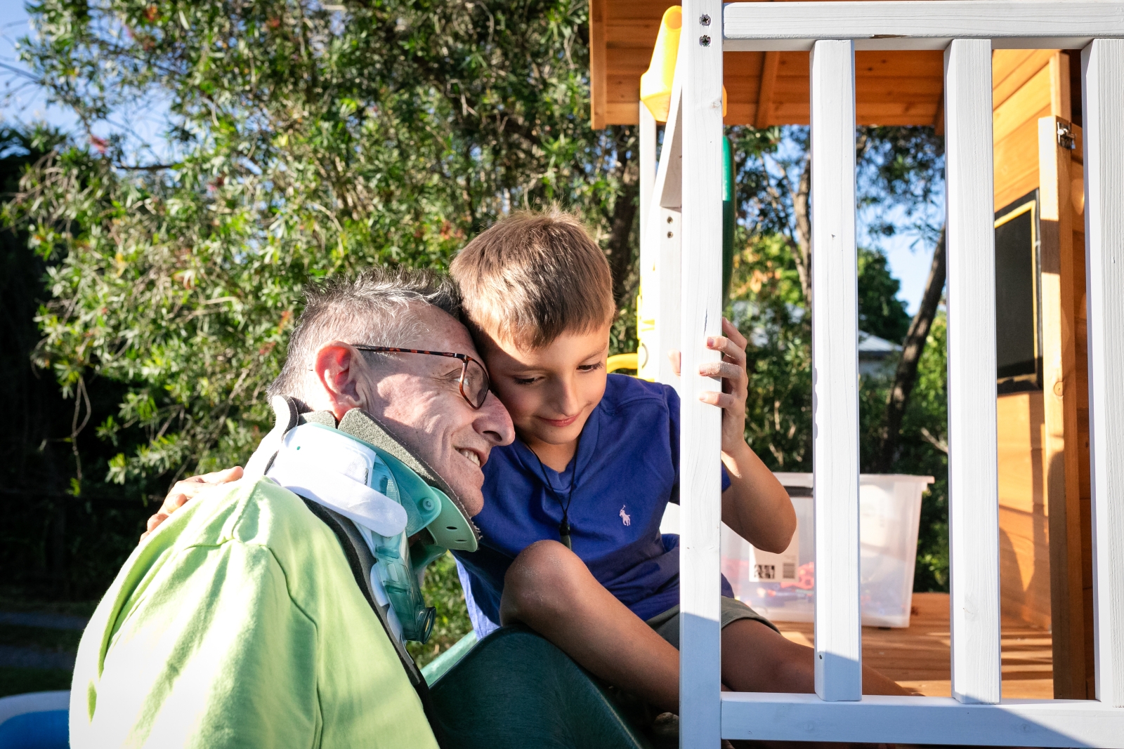 Grandfather and grandson embrace in the backyard on the playground