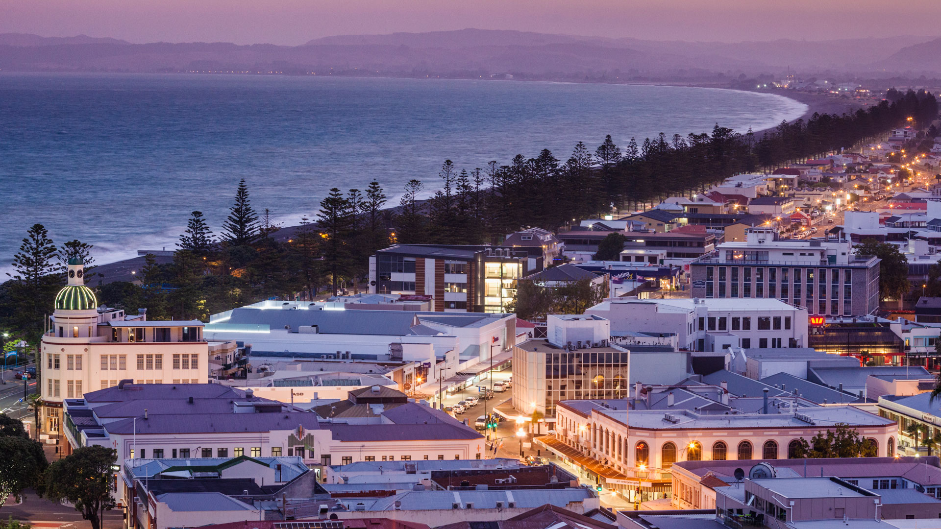 An aerial shot of Napier at sunset, with a bird's eye view of the city looking out towards the sea.